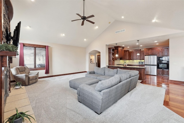 living room featuring high vaulted ceiling, light hardwood / wood-style floors, and ceiling fan