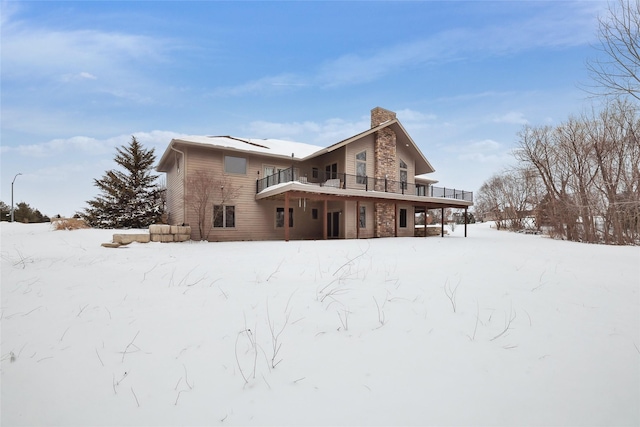 snow covered house featuring a chimney