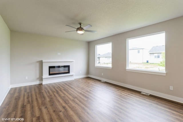 15019 Springbrook Trl, Urbandale, IA 50323 - unfurnished living room with wood finished floors, a glass covered fireplace, a ceiling fan, and a textured ceiling