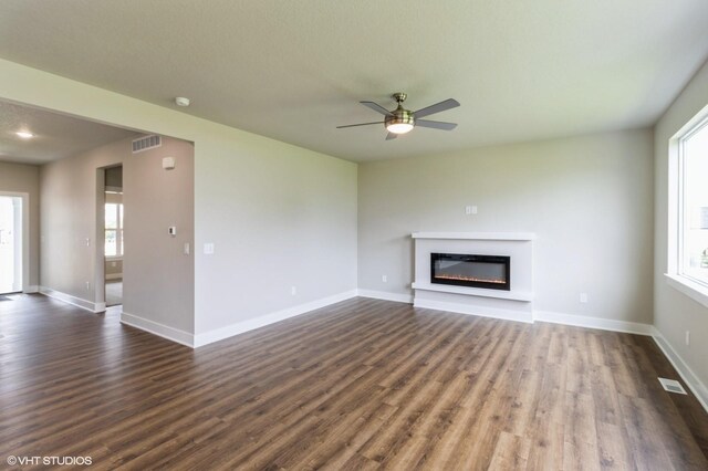 15019 Springbrook Trl, Urbandale, IA 50323 - unfurnished living room featuring healthy amount of natural light, a glass covered fireplace, and dark wood finished floors