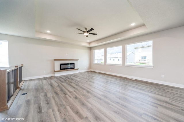 15015 Springbrook Trl, Urbandale, IA 50323 - unfurnished living room with a raised ceiling, wood finished floors, a ceiling fan, recessed lighting, and a glass covered fireplace