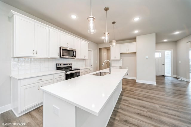 15015 Springbrook Trl, Urbandale, IA 50323 - kitchen featuring appliances with stainless steel finishes, a center island with sink, decorative backsplash, white cabinets, and recessed lighting