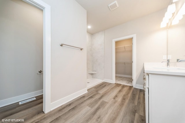 15015 Springbrook Trl, Urbandale, IA 50323 - full bathroom featuring vanity, wood finished floors, walk in shower, a walk in closet, and recessed lighting