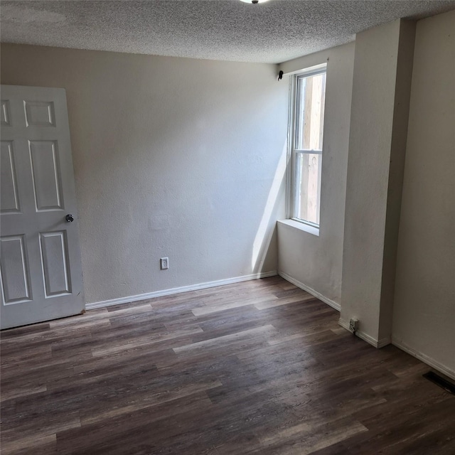 empty room with a textured ceiling and dark hardwood / wood-style flooring