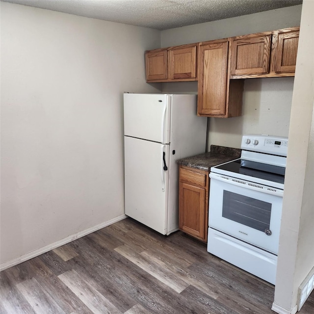 kitchen featuring dark wood-type flooring, white appliances, and a textured ceiling