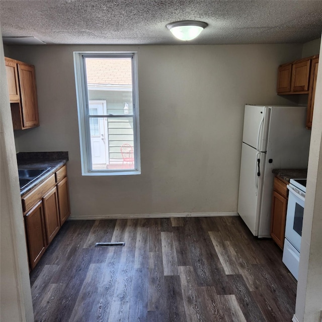 kitchen featuring dark hardwood / wood-style flooring, a wealth of natural light, and white appliances