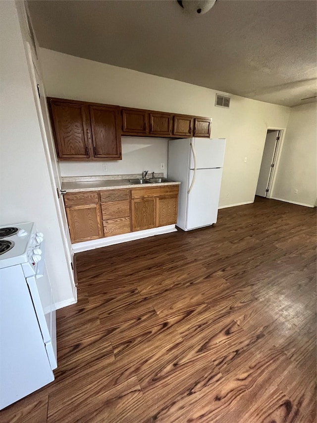 kitchen featuring sink, white appliances, dark hardwood / wood-style floors, and a textured ceiling