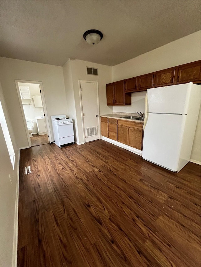 kitchen with sink, white appliances, and dark wood-type flooring