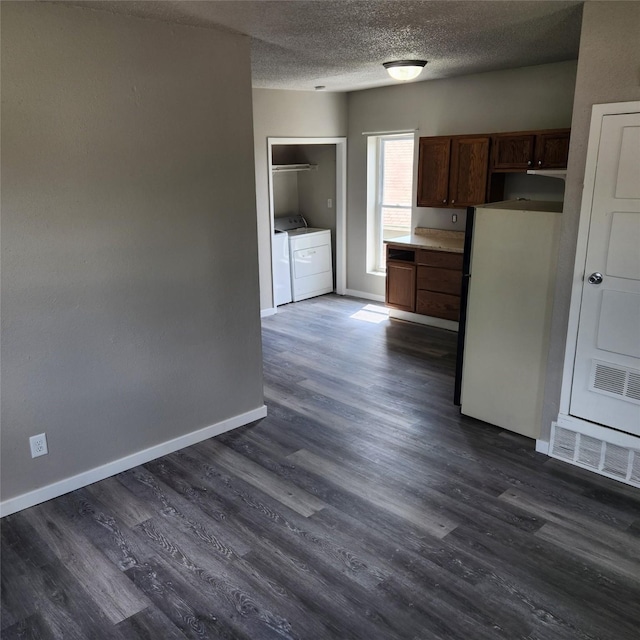 kitchen with white refrigerator, washing machine and dryer, dark hardwood / wood-style floors, and a textured ceiling