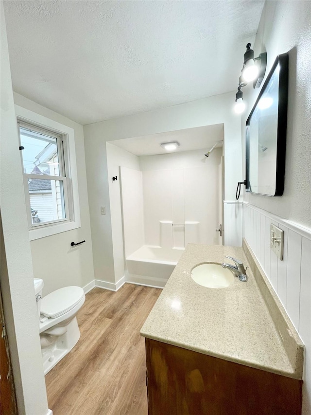 full bathroom with toilet, wood-type flooring,  shower combination, a textured ceiling, and vanity