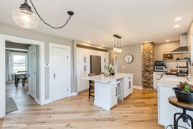 kitchen with black microwave, a kitchen island, white cabinetry, wall chimney exhaust hood, and tasteful backsplash