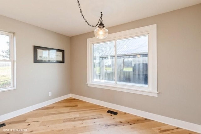 unfurnished dining area featuring light wood-type flooring, visible vents, and baseboards