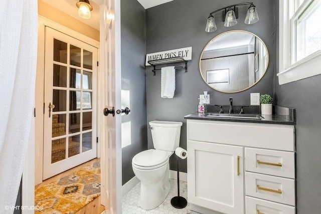 bathroom featuring toilet, baseboards, french doors, and vanity