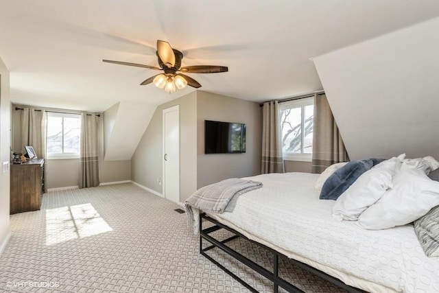 carpeted bedroom featuring multiple windows, baseboards, vaulted ceiling, and a ceiling fan