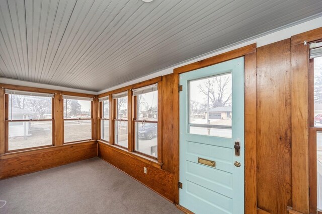 unfurnished sunroom featuring carpet and wood walls