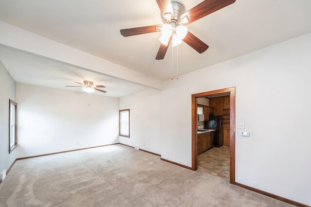 empty room featuring baseboards, a ceiling fan, and light carpet