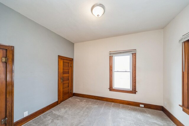 unfurnished room with baseboards and light colored carpet