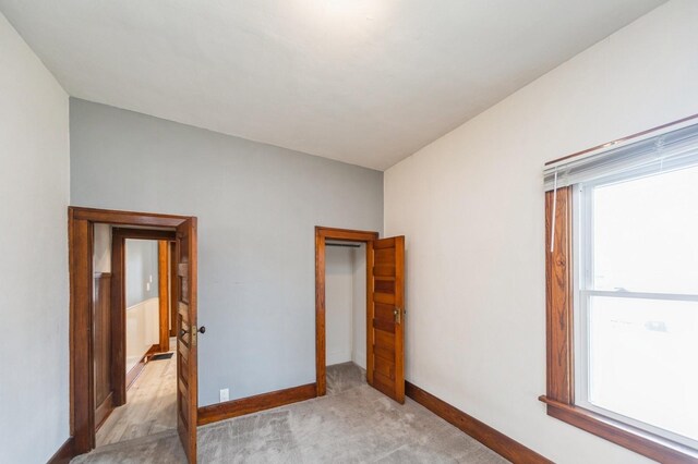 unfurnished bedroom featuring baseboards and light carpet