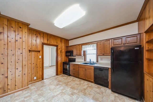 kitchen with wooden walls, light countertops, stone finish flooring, ornamental molding, and black appliances