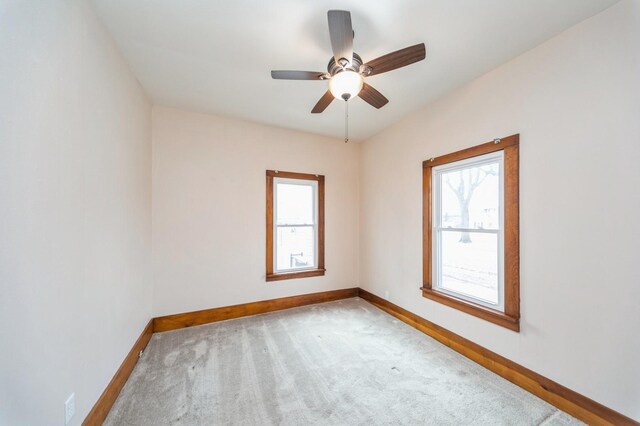 carpeted spare room with a ceiling fan, baseboards, and plenty of natural light