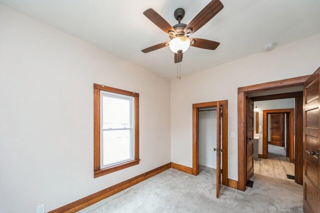 unfurnished bedroom with baseboards, ceiling fan, a closet, and light colored carpet