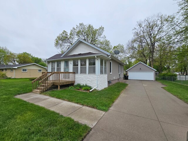 bungalow-style house with fence, stone siding, a detached garage, a front yard, and an outbuilding