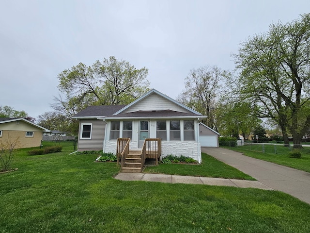 bungalow-style home featuring a garage, fence, stone siding, and a front yard