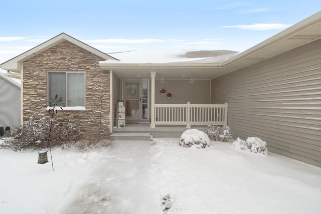 snow covered property entrance with a porch