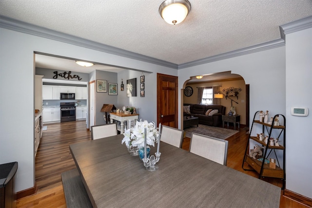 2711 Westover Blvd, Des Moines, IA 50322 - dining room with arched walkways, a textured ceiling, crown molding, and wood finished floors
