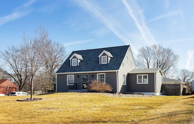 new england style home featuring roof with shingles, a front yard, and fence