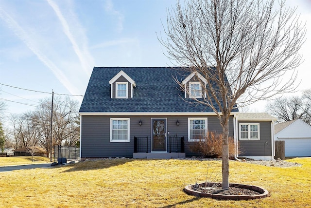 cape cod home featuring an outbuilding, a garage, a shingled roof, and a front lawn