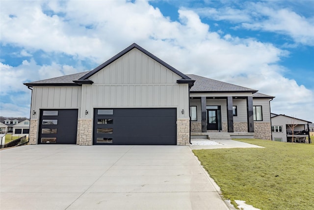 modern farmhouse with stone siding, board and batten siding, an attached garage, and a front lawn