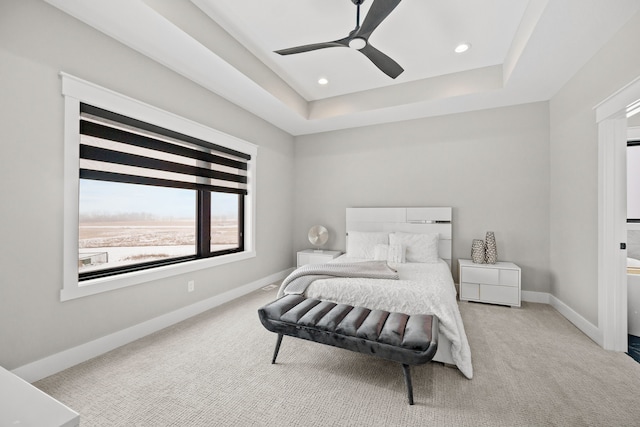 carpeted bedroom with ceiling fan and a tray ceiling