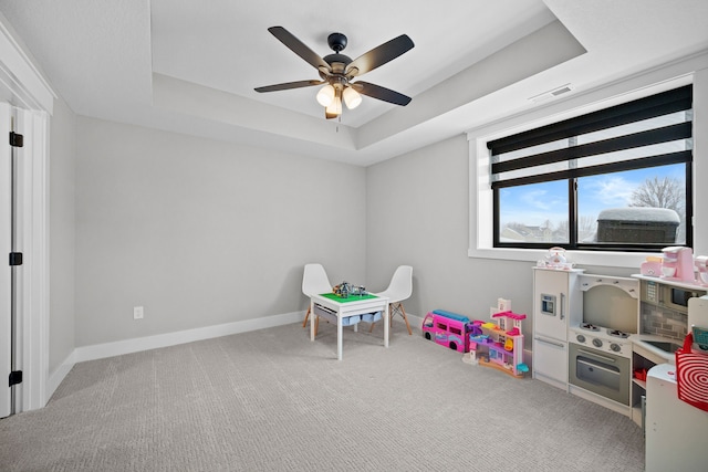 playroom featuring ceiling fan, carpet flooring, and a raised ceiling