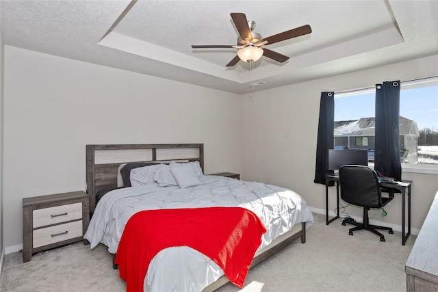 bedroom featuring ceiling fan, a raised ceiling, light carpet, and a textured ceiling