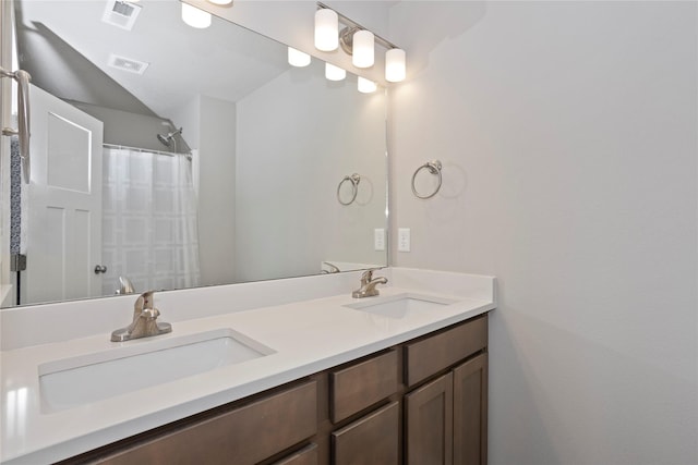 bathroom with curtained shower, double vanity, visible vents, and a sink