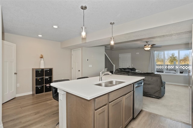 kitchen with sink, decorative light fixtures, a center island with sink, a textured ceiling, and stainless steel dishwasher