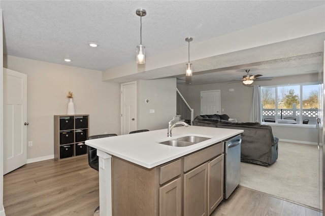 kitchen featuring stainless steel dishwasher, a sink, a center island with sink, a textured ceiling, and open floor plan