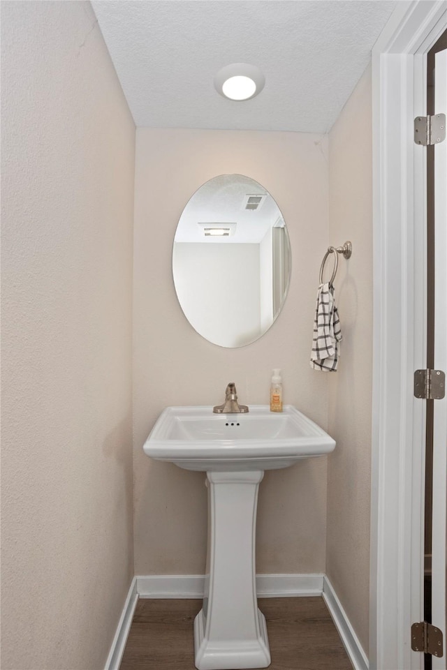 bathroom with baseboards, wood finished floors, and visible vents