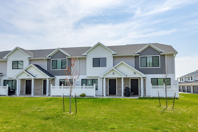 townhome / multi-family property featuring stone siding, a front yard, and fence