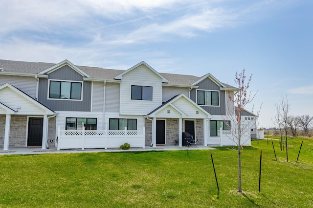 view of property with board and batten siding, stone siding, and a front yard