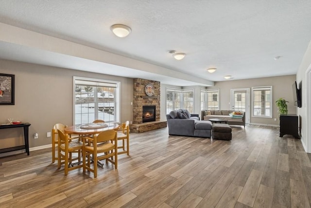 dining space with a textured ceiling, a fireplace, and light hardwood / wood-style flooring