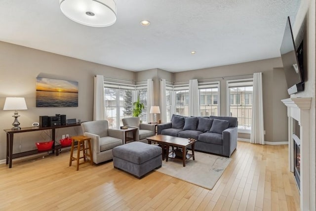 living room featuring plenty of natural light, a textured ceiling, and light wood-type flooring