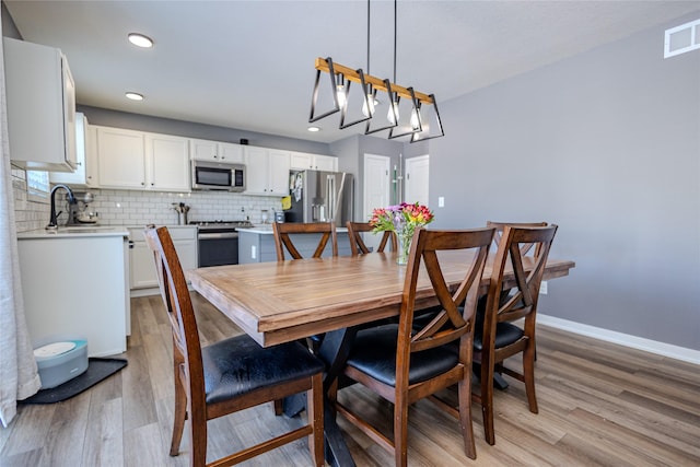 dining area with sink and light hardwood / wood-style floors