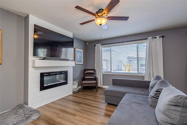 living room featuring ceiling fan, hardwood / wood-style floors, and a textured ceiling