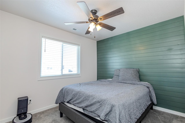 bedroom featuring carpet floors, a textured ceiling, ceiling fan, and wood walls