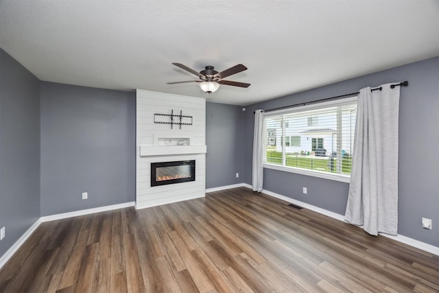 610 NE Whitetail Dr, Ankeny, IA 50021 - unfurnished living room featuring a large fireplace, wood finished floors, and ceiling fan