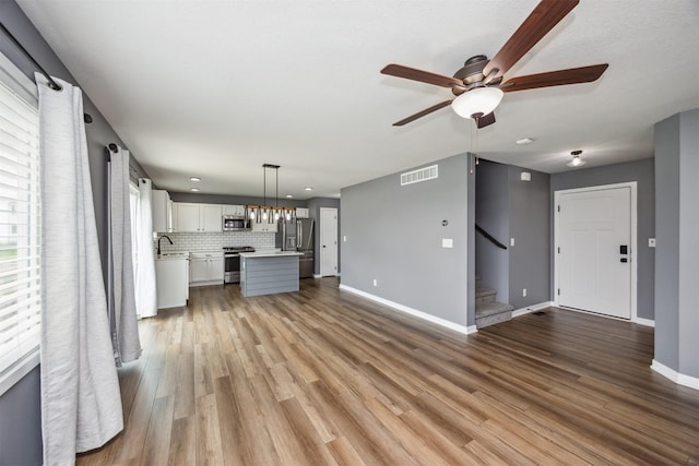 610 NE Whitetail Dr, Ankeny, IA 50021 - unfurnished living room featuring a ceiling fan, stairway, and light wood-style flooring