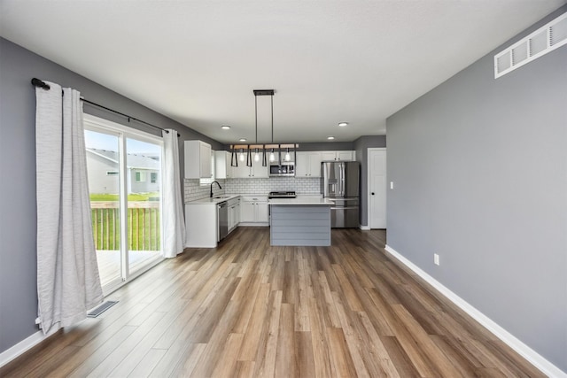 610 NE Whitetail Dr, Ankeny, IA 50021 - kitchen with stainless steel appliances, light countertops, wood finished floors, tasteful backsplash, and white cabinetry