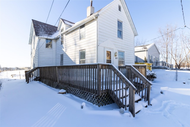 snow covered rear of property featuring a deck